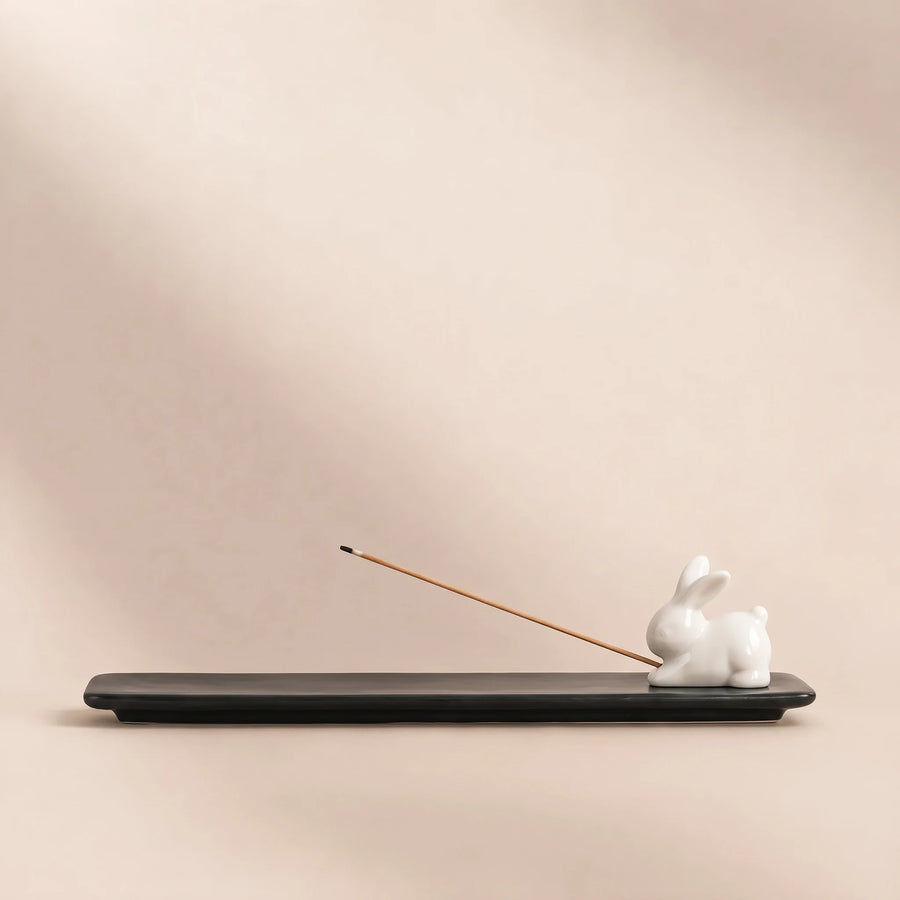 Black ceramic incense stick tray with a small white rabbit figurine