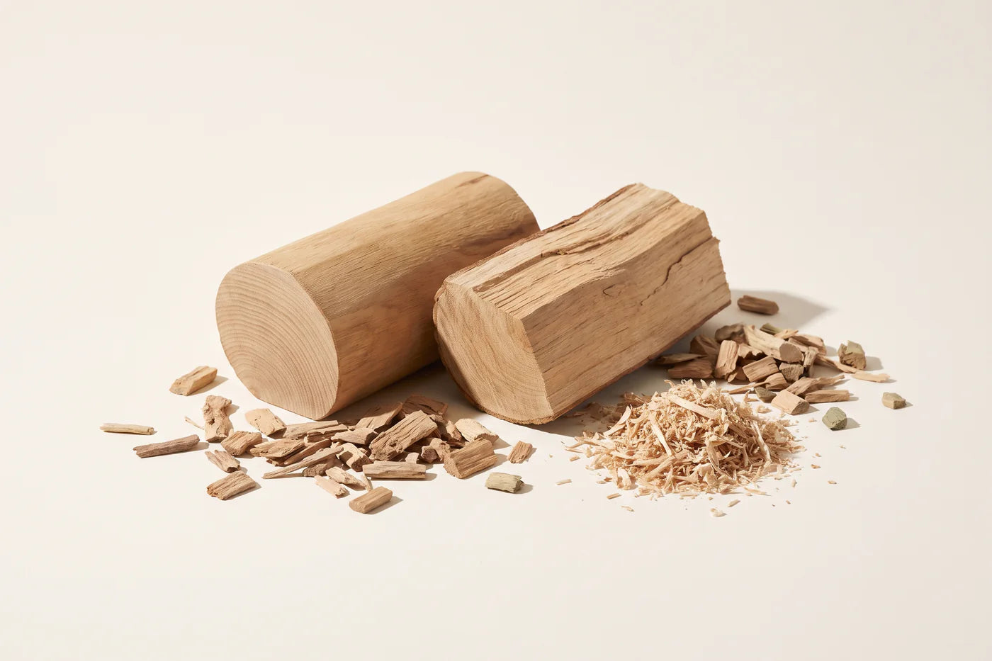 Two billets of sandalwood heartwood, one sawn face and one split face, with chips and fine shavings.