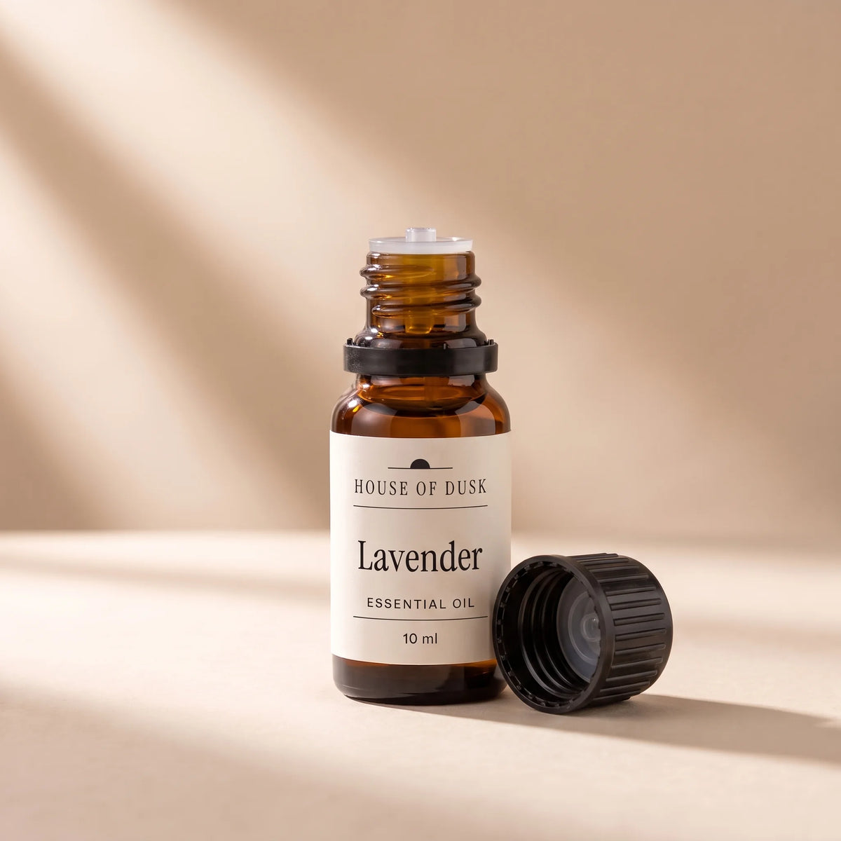 Open 10 ml amber essential oil bottle showing the dropper insert, black cap beside it
