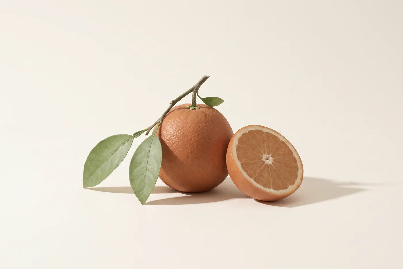 A whole sweet orange with its calyx and twig, three leaves, and a fresh half showing the segments.